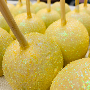 a row of yellow cake pops with sparkle on them