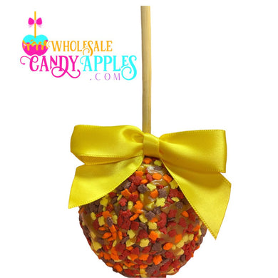 A candy apple with a yellow ribbon tied around it, decorated with colorful candy pieces.