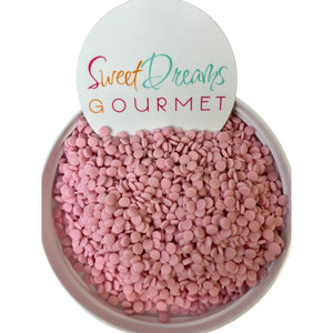 a bowl filled with pink candy beans next to a sign that says sweet dreams go