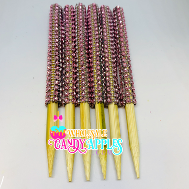 a group of pink and yellow beads on wooden sticks