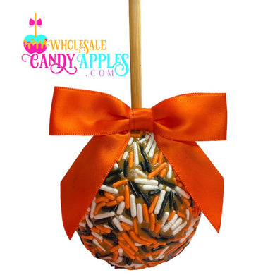 An orange candy apple with a red ribbon and sprinkles, displayed against a white background.