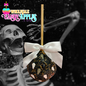 A candy apple with a white ribbon and a spooky skeleton in the background.