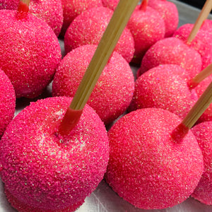 a close up of pink donuts with sticks sticking out of them
